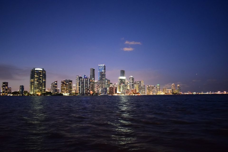 Brickell towers lit at dusk across the water of Biscayne Bay