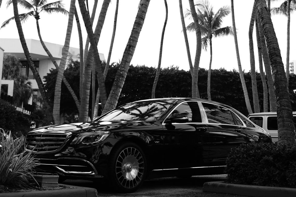 Black Mercedes-Maybach sedan parked under tall palm trees in Miami
