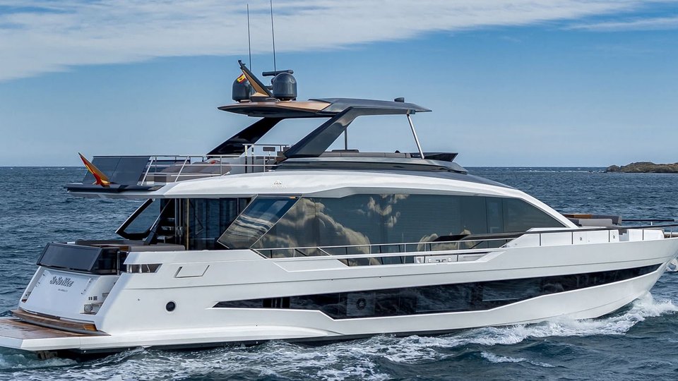 Side view of a white motor yacht under way, flybridge up
