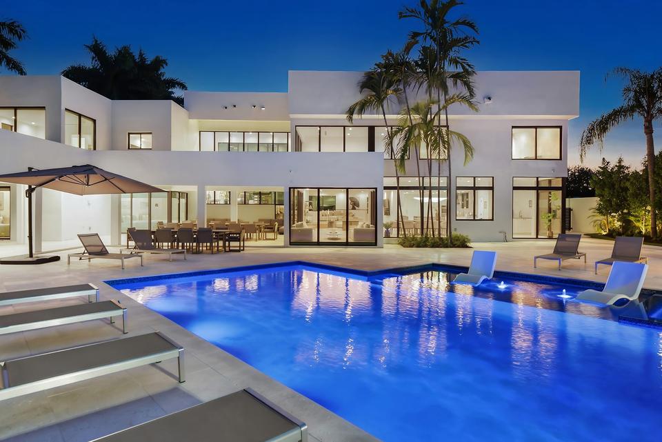 Villa Palma illuminated pool and modern white villa at twilight, Miami luxury rental