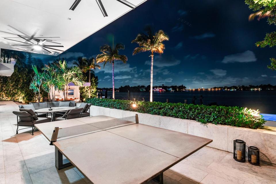 Covered outdoor terrace with ping pong table at night, Villa Lavoro, Miami Beach luxury rental
