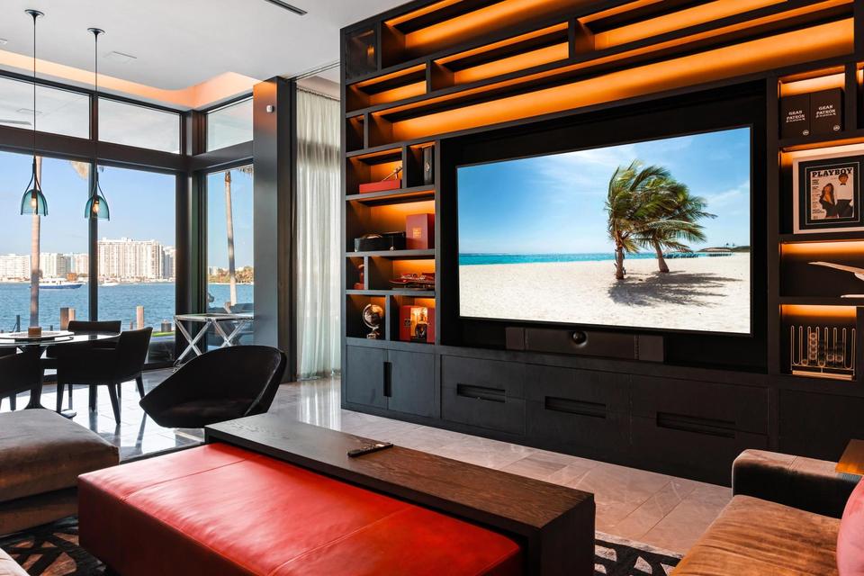 Media lounge with walnut shelving wall and large screen, Villa Lavoro, Miami Beach luxury rental