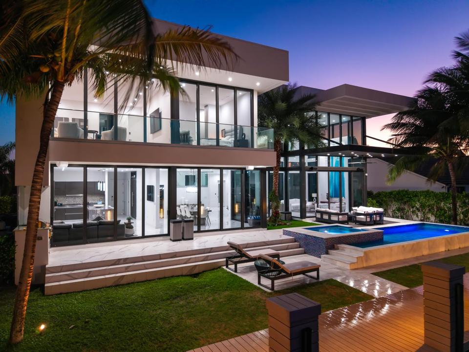 Villa Estan at dusk, pool and two-storey glass facade, Eastern Shores, North Miami Beach luxury rental