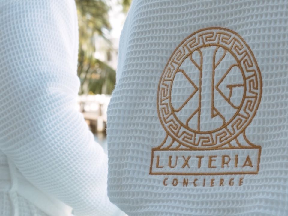 White robe embroidered with the Luxteria Concierge logo