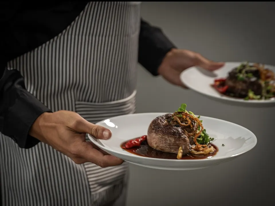 Waiter serving plated steak dinners at a private event in Miami