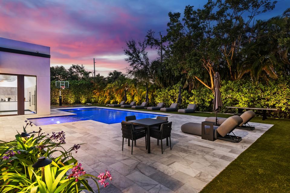 Pool terrace with lounge seating at dusk, Villa Meimon, North Miami Beach