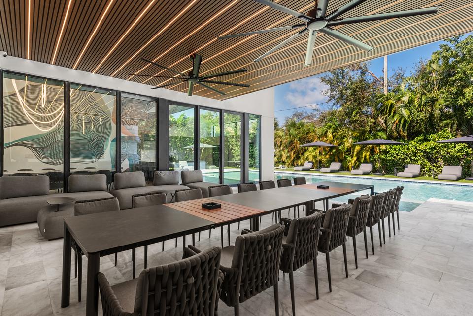 Covered terrace with a long dining table and lounge, Villa Meimon, North Miami Beach