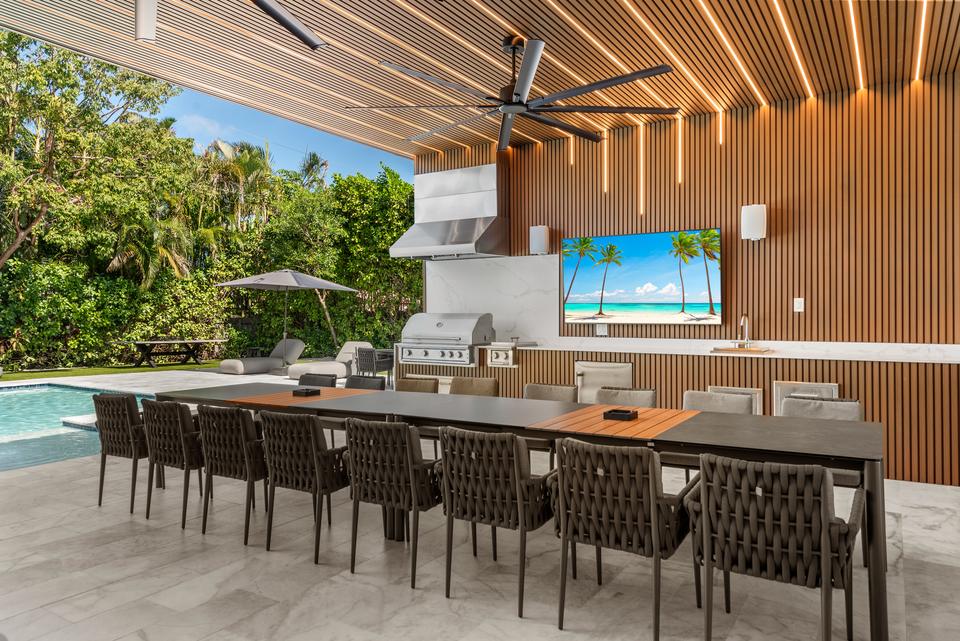 Long outdoor dining table beside the pool, Villa Meimon, North Miami Beach