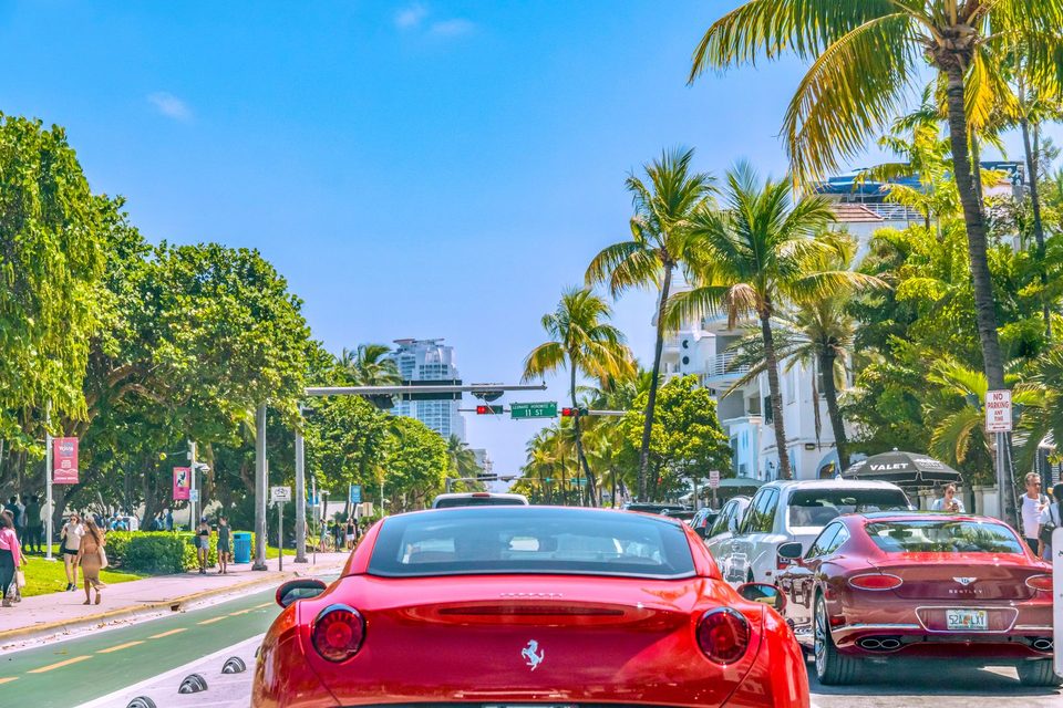 Red Ferrari on a palm-lined Miami street