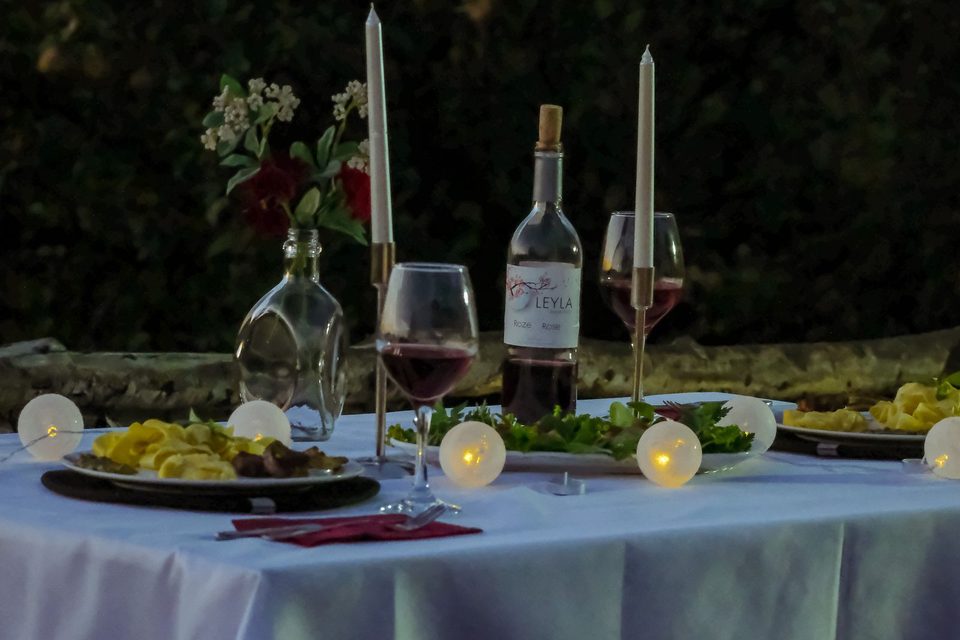 Table set with candles and wine in a garden, ready for guests