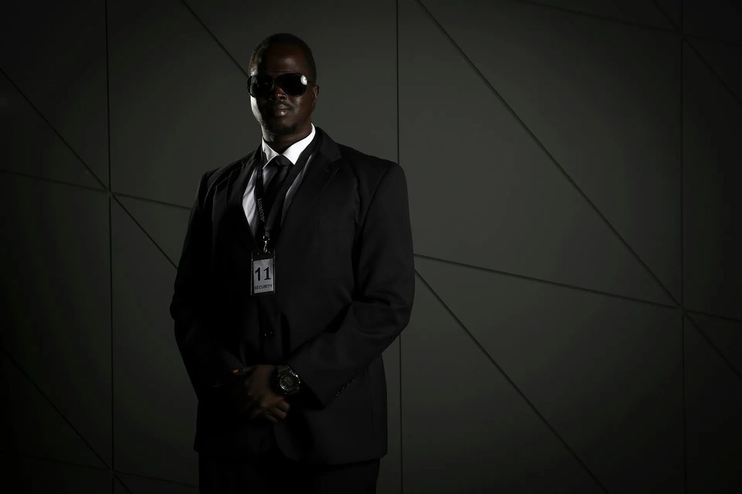 Bodyguard in a dark suit and sunglasses with a security credential