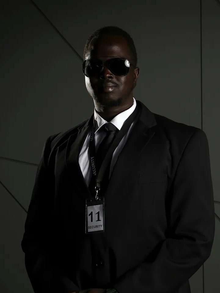 Bodyguard in a dark suit and sunglasses with a security credential
