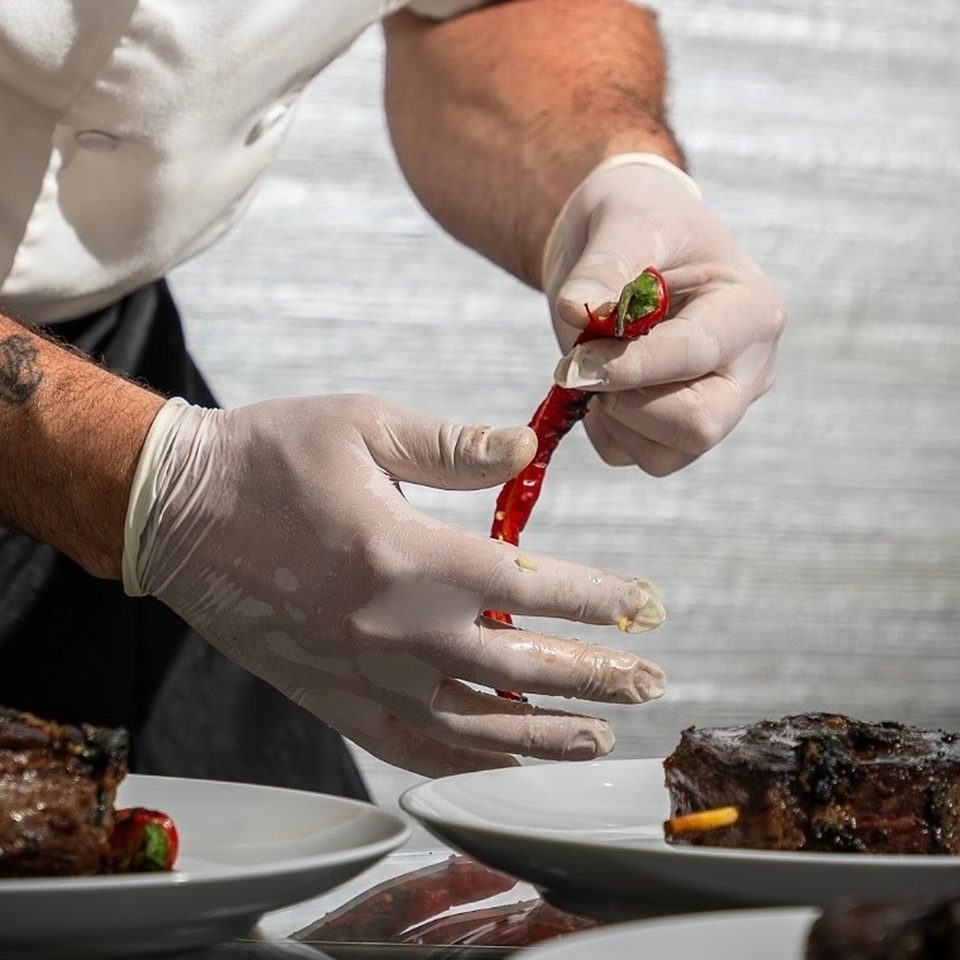 Private chef finishing plates, hands only