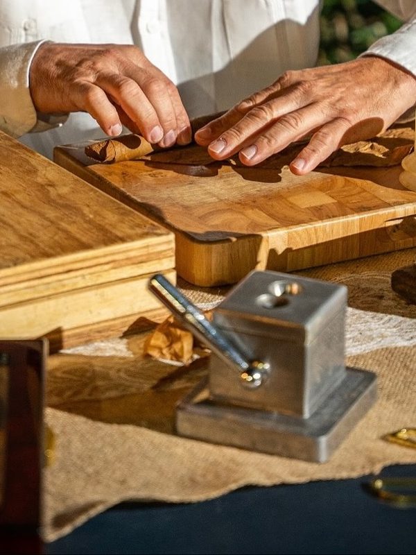 Hands rolling a cigar at a wooden cigar station