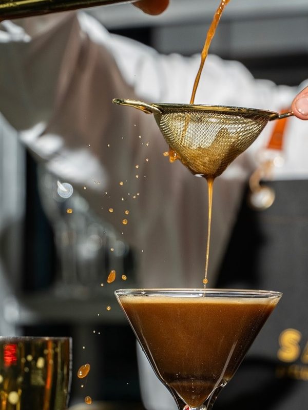 Bartender straining an espresso martini into a coupe