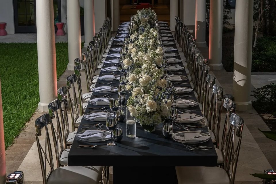 Long dinner table with white floral centerpieces at a Miami villa event