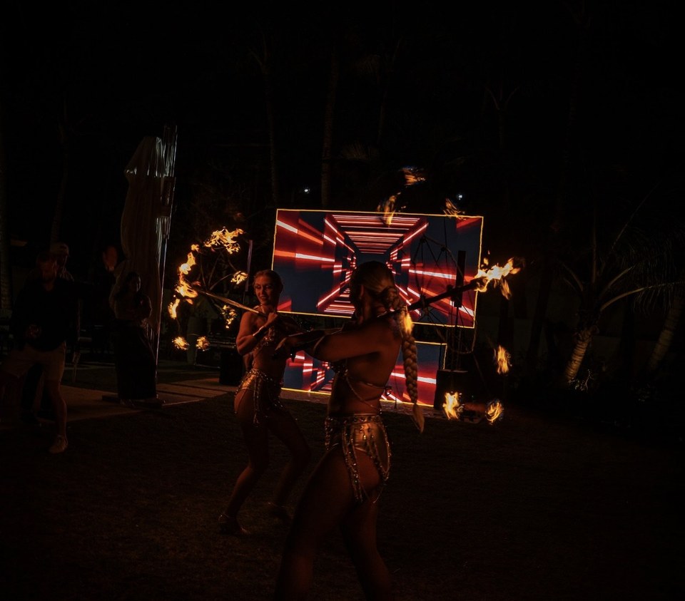 Fire dancers performing with flaming staffs at a private nighttime event in Miami