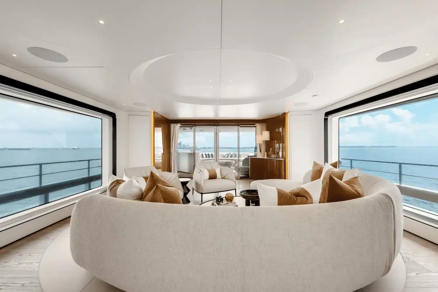 Main salon with a curved sofa and panoramic windows on the 118 foot Azimut yacht in Miami