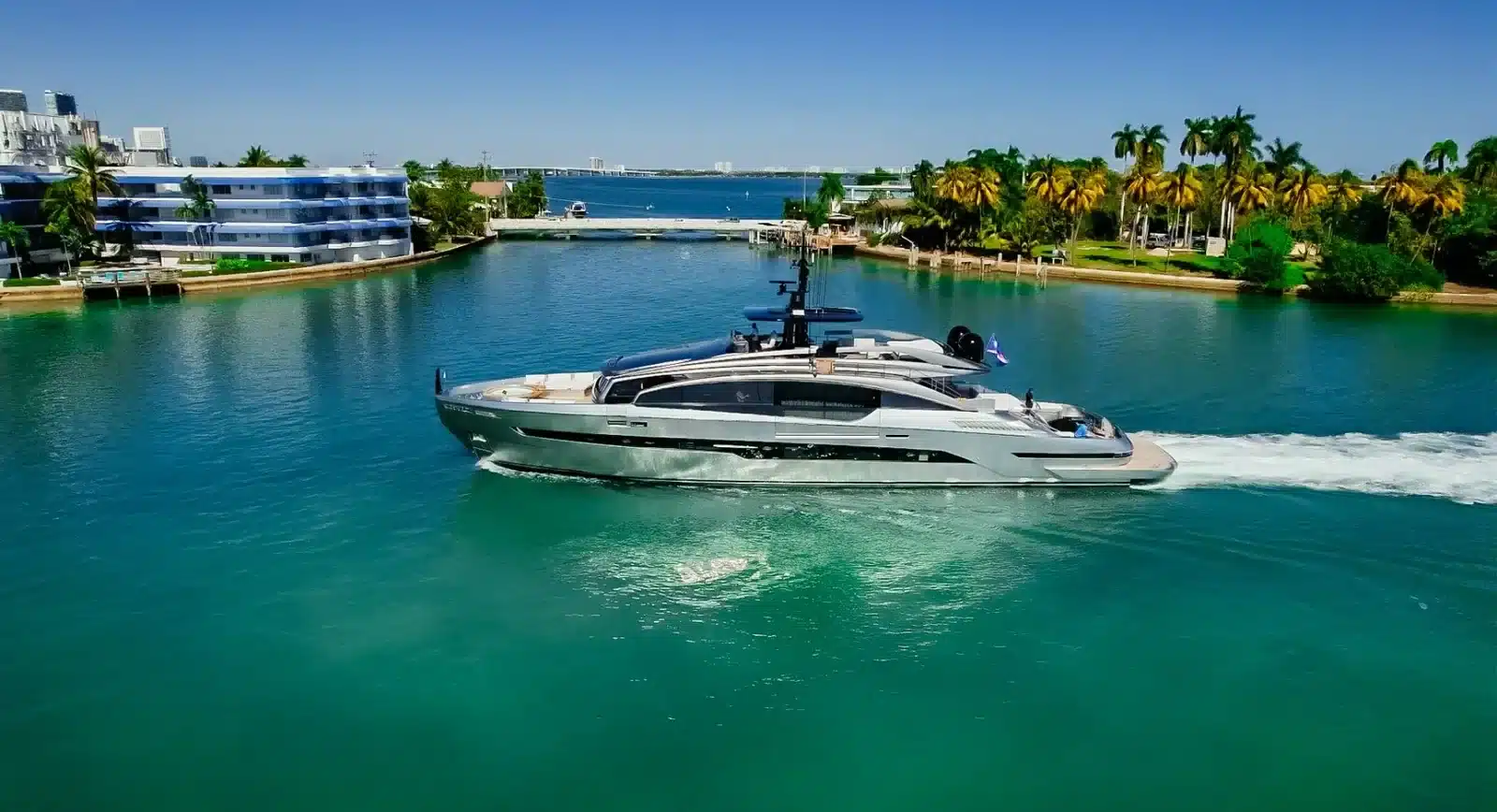 The 116 foot Pershing GTX cruising across turquoise water past waterfront homes and palms in Miami