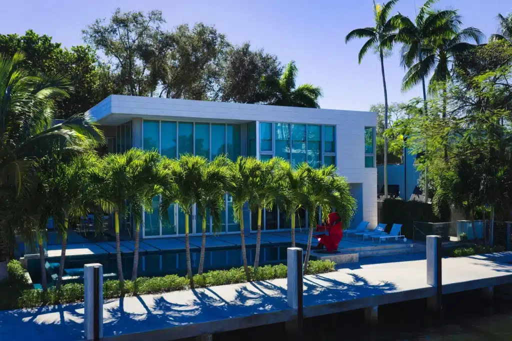 Modern waterfront villa with palm trees and a boat dock in South Florida