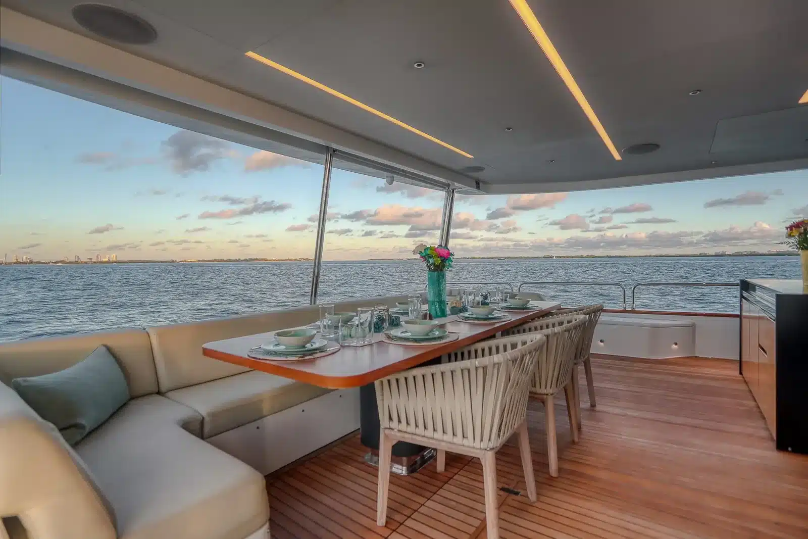 Shaded aft deck dining table set at sunset on the 88 foot Sirena yacht over Biscayne Bay