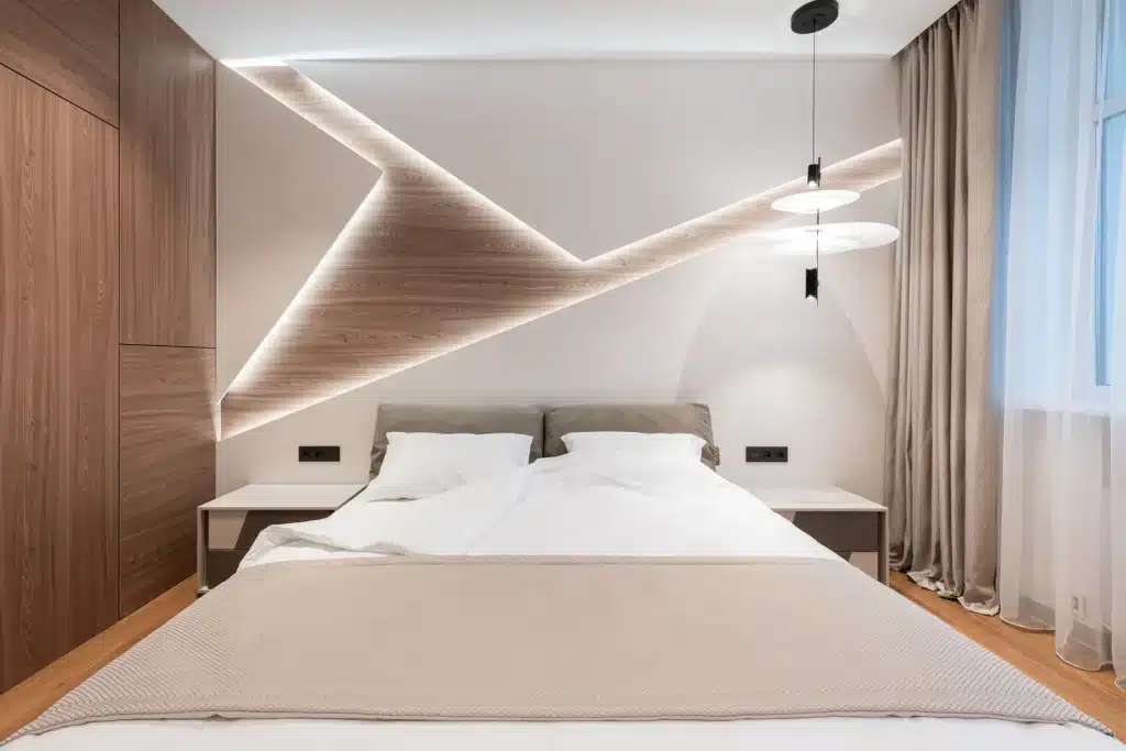 Bright minimalist hotel suite with a made bed, warm wood accents and soft lighting