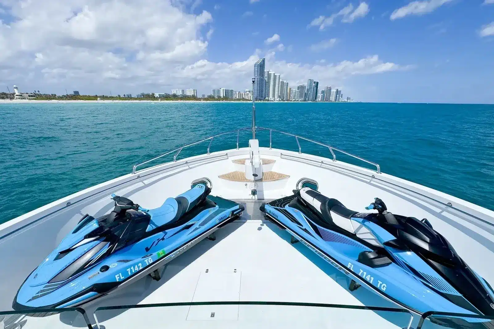 Yacht bow with jet skis on deck and the Miami Beach skyline ahead