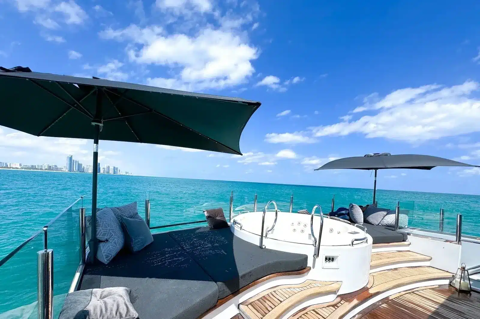 Shaded deck lounge with a hot tub on a 112 foot yacht, Miami Beach skyline in the distance